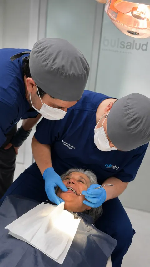 Doctor y asistente de CPH Salud con gorro y mascarilla atendiendo a una paciente