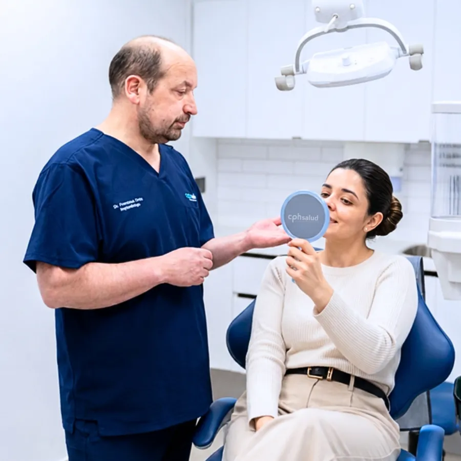 Dr. Francisco Ortiz mostrando el resultado del tratamiento con un espejo de mano a una paciente de CPH Salud
