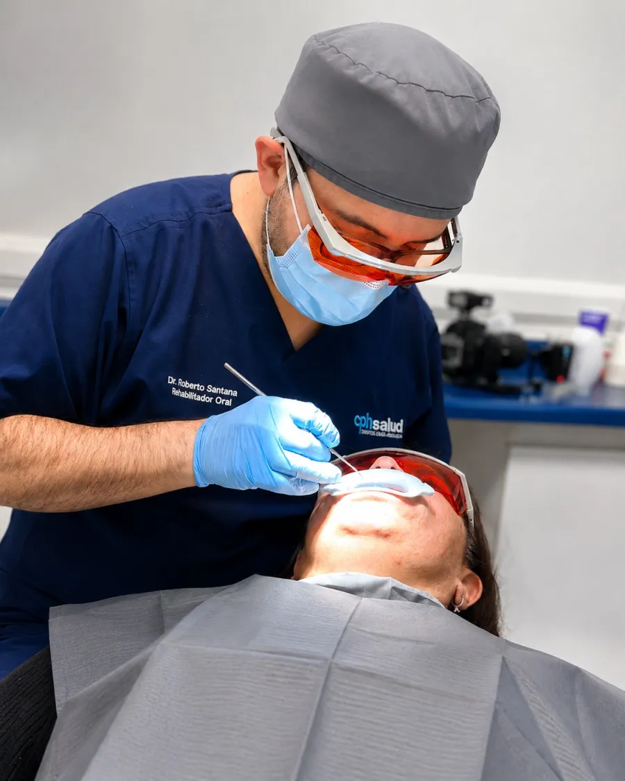 Dr. Roberto Santana aplicando un blanqueamiento dental con lámpara a una paciente en CPH Salud