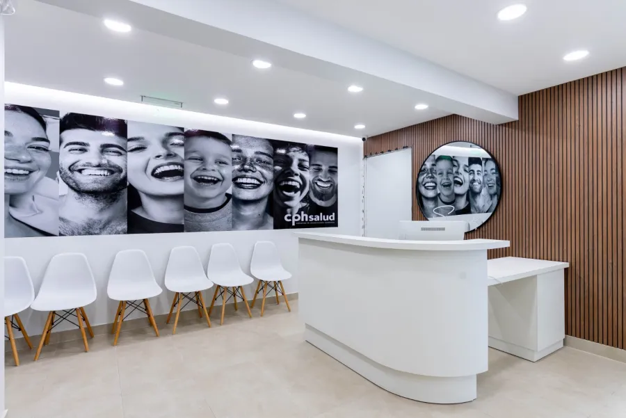 Recepción de CPH Salud con mural de sonrisas, sillas de espera y muro de madera