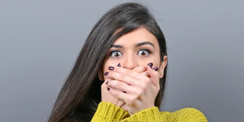 Mujer sorprendida cubriéndose la boca con ambas manos