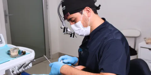 Odontólogo de CPH Salud con lupas de aumento revisando a un paciente en el sillón dental